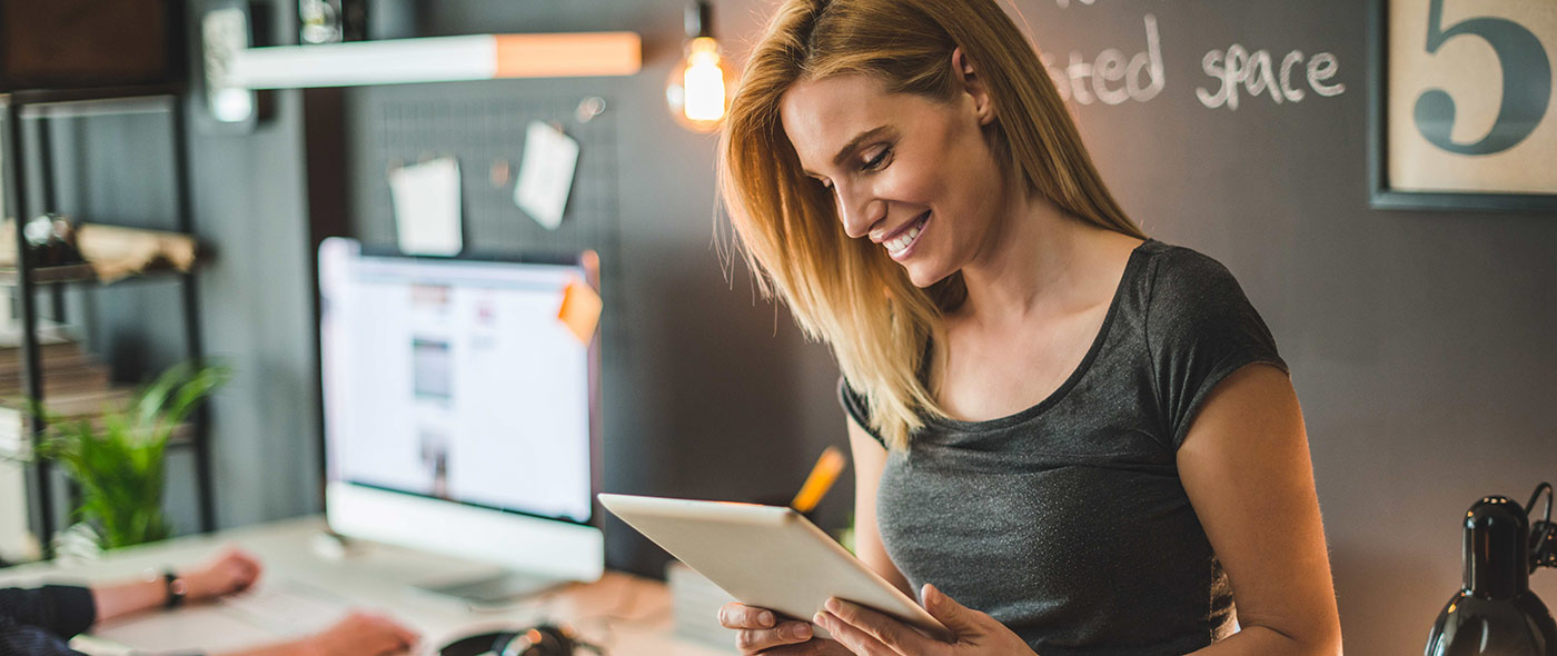 Femme souriant au travail avec une tablette