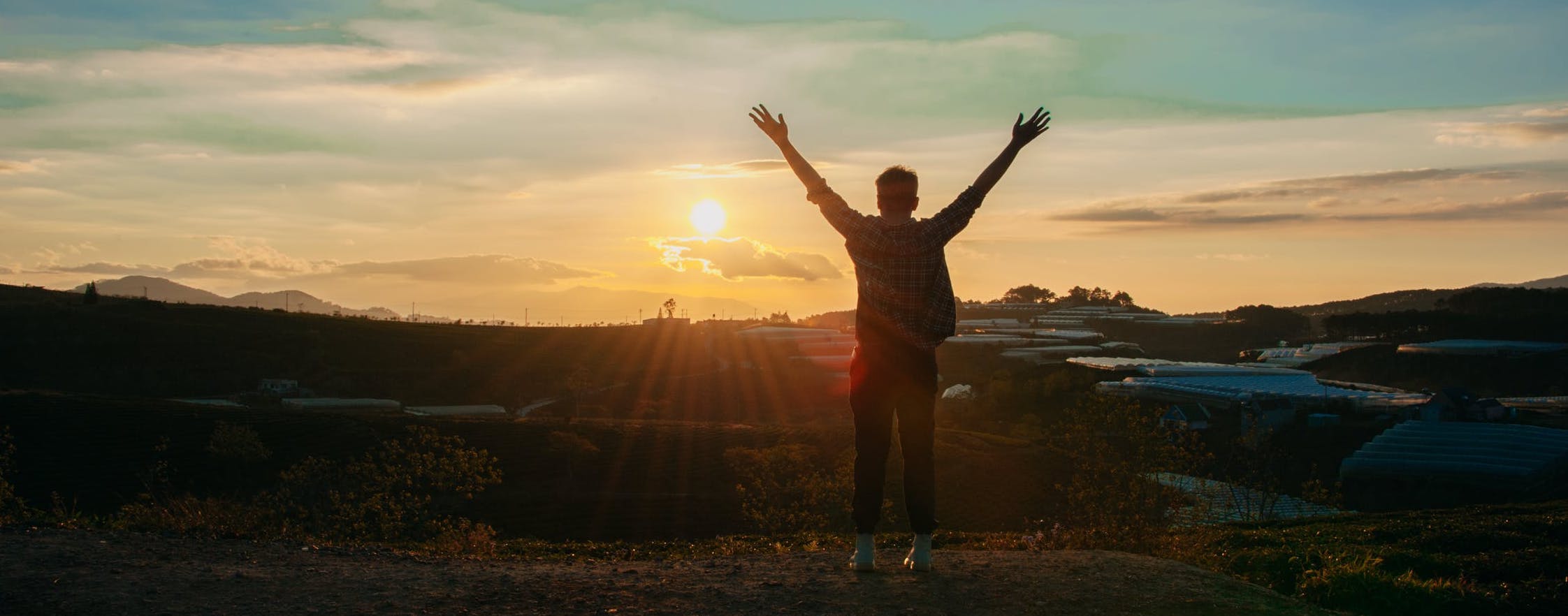 Homme regardant le levé du soleil les bras en l'air