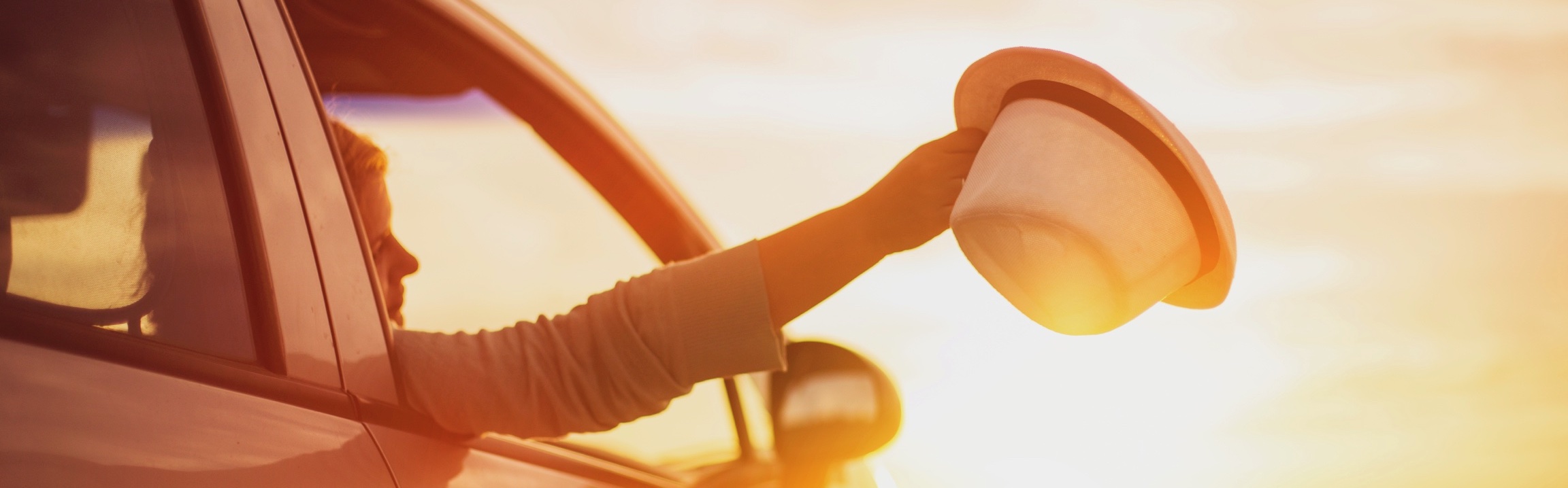 Une femme sort son chapeau par la fenêtre de la voiture