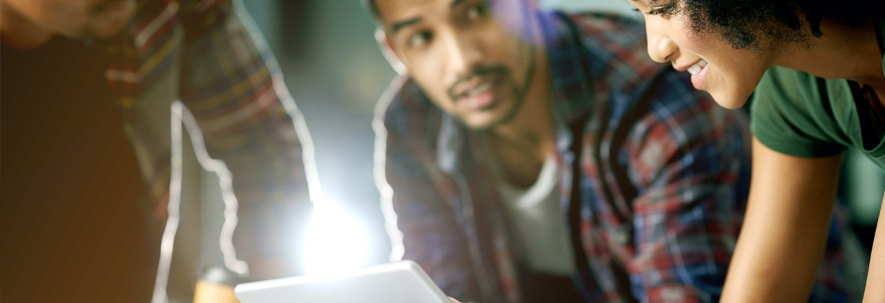 trois personnes sont en train de regarder une tablette tactile