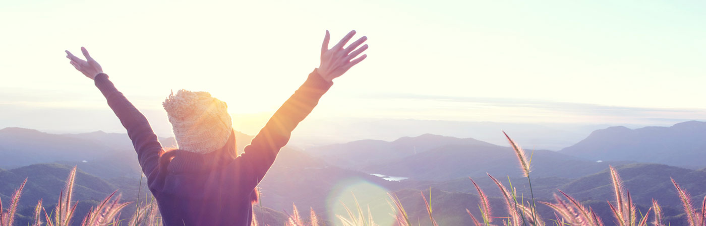 Femme levant les bras au ciel en montagne