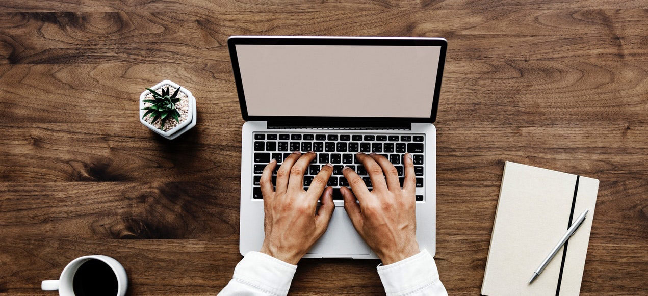 Clavier ordinateur mac vu depuis le haut avec un cafe et une plante