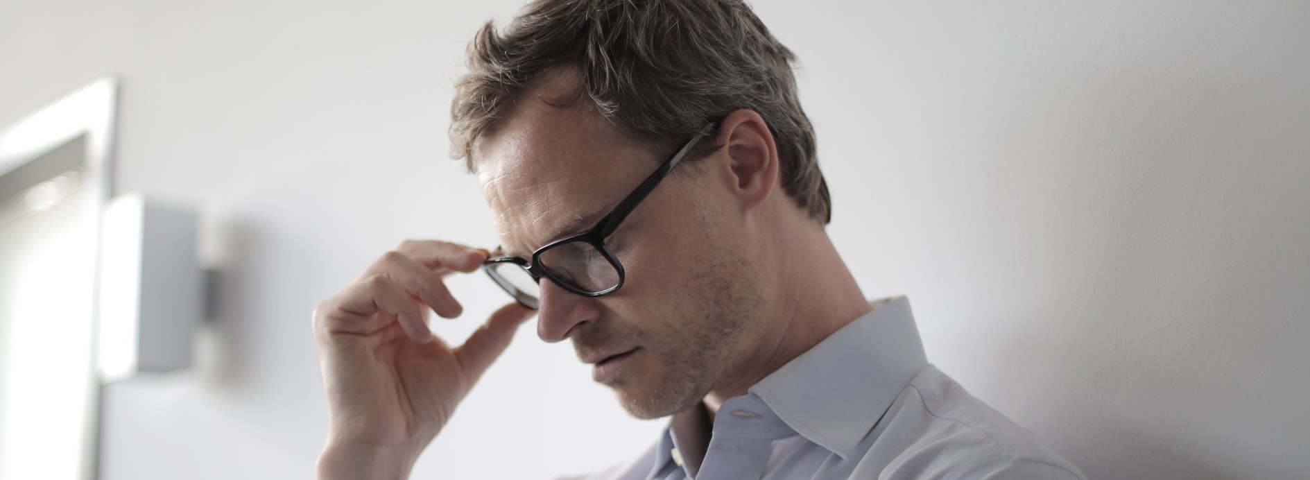 Une homme anxieux se tient les lunettes